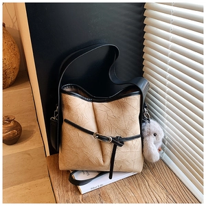 Detail of beige tote bag featuring pleated rock texture and black contrast shoulder strap