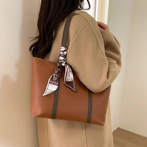 Brown leather tote bag with silk scarf detail worn with a beige wool coat for work