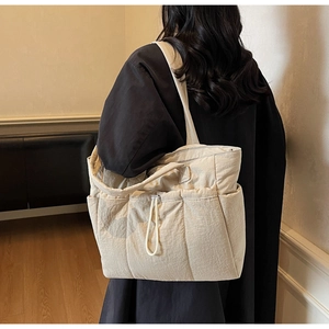 Quilted beige puffer tote bag featuring side pockets and adjustable drawstring detail
