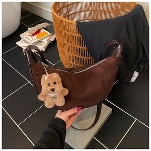 Detail of brown suede hobo bag with teddy bear pendant and smooth leather strap