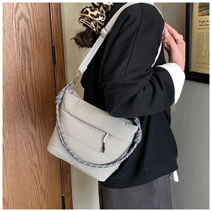 Detail of light gray puffy crossbody bag with woven rope decor and adjustable strap