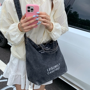 Close-up of dark grey denim tote bag with white Leisurely Carefree artistic printing