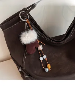 Détail du charm gant en peluche avec perles colorées sur un sac cabas en cuir marron