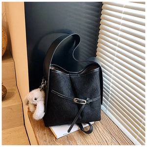 Detail of black pleated shoulder bag with metal ring buckle and white plush bunny charm