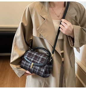 Detailed view of vintage tweed crossbody bag with golden clasp and leather handle straps