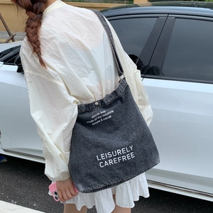 Detail of large denim tote bag with white lettering print on asphalt background