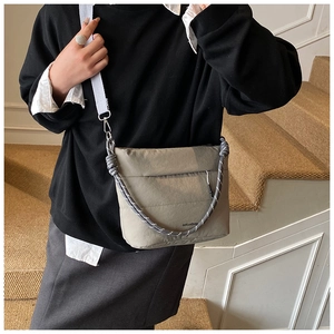 Close-up of khaki crossbody bucket bag featuring a black and white braided rope handle