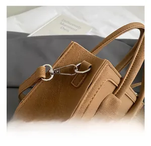 Detailed close-up of the vintage brown handbag's silver metal lobster clasp and strap