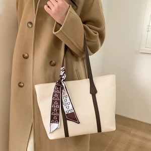 Detail of vintage tote bag with brown straps and bear print silk scarf on a wool coat