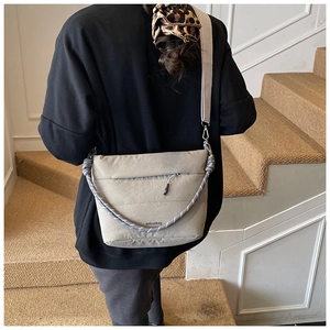 Detail view of khaki bucket bag featuring textured lanyard and wide woven shoulder strap
