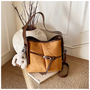 Detail of caramel vintage bucket bag with pleated texture and white rabbit charm