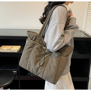 Detailed view of olive green quilted nylon tote bag with drawstring side and wide strap