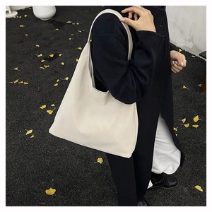 Close-up of minimalist cream hobo bag worn with black coat for autumn commute