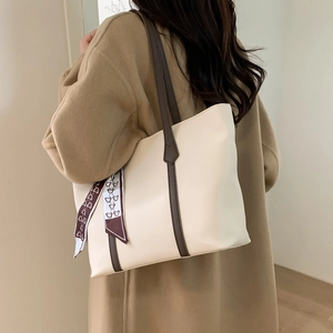 Detail view of large tote bag with cream leather finish and decorative bear silk scarf