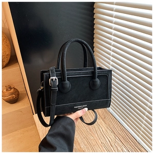 Detailed view of black matte leather texture and silver hardware on a crossbody handbag