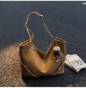 Gros plan d'un cabas en cuir marron avec boucle et breloque en peluche sur le trottoir