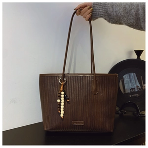 Detail of dark brown tote bag with herringbone weave and retro wooden beaded charm