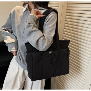 Close-up of black quilted nylon tote bag with drawstring pocket and spacious side storage