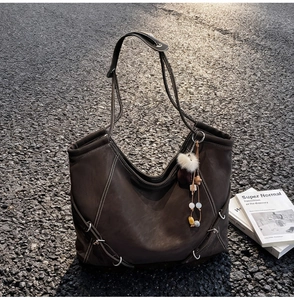 Détail du sac fourre-tout marron café avec surpiq coutures blanches et charme sur l'asphalte