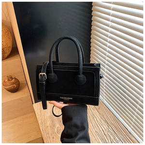 Detailed macro view of matte black leather handbag with embossed gold fashion lettering
