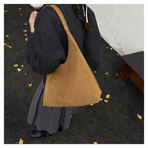 Detail of a large camel hobo bag in faux suede on a street background with yellow leaves