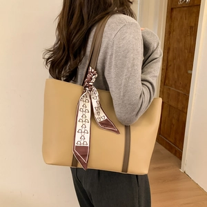 Close-up of khaki tote bag with matte texture and decorative silk scarf on shoulder strap