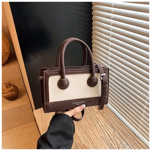Detail of vintage contrast color handbag featuring round handle joints and logo print