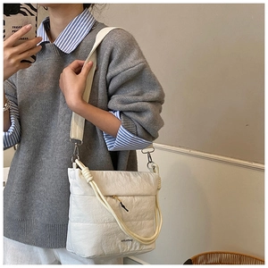 Detailed view of a white quilted crossbody bag featuring a unique knotted handle design