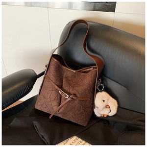 Detail of dark brown bucket bag featuring pleated texture and cute white plush bunny charm