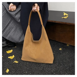 Close-up of a large tan leather tote bag shown in an autumnal outdoor lifestyle setting
