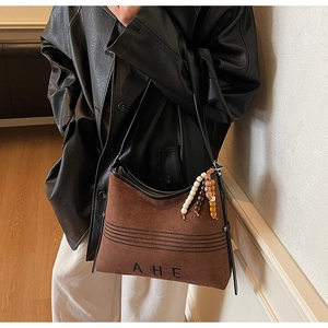 Detail of vintage suede tote bag with leather straps and decorative bead tassels