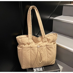 Detail of light khaki tote bag featuring pleated fabric and three front drawstring pockets