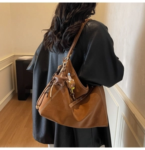 Detail view of large brown suede hobo bag featuring cute bear plush and star leather tag