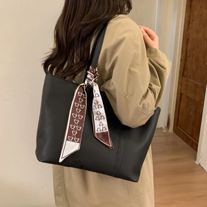 Detail view of large black tote bag with bear print scarf on a khaki trench coat