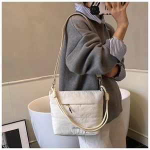 Detail of white quilted cloud bag with thick rope strap shown on a female model