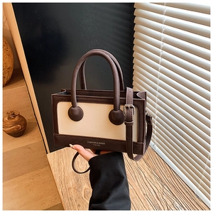 Close-up of a structured brown and cream handbag with double handles and YIMING branding