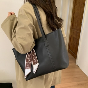 Detailed view of black PU leather tote bag with silk scarf on a trench coat model