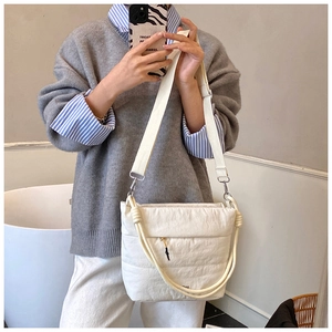 Detailed close-up of quilted puffy white crossbody bag with decorative rope knots