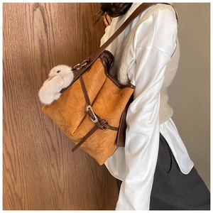 Detail of vintage brown textured bucket bag with silver buckle and plush rabbit charm
