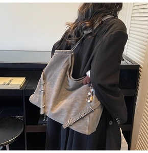 Détail du sac cabas en cuir taupe avec boucles métalliques et pompon sur un modèle