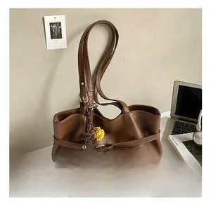 Brown suede tote bag detail featuring a decorative belt strap and plush floral charm