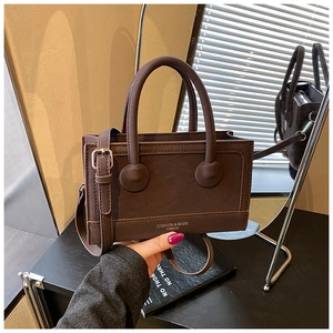 Detail view of dark brown retro handbag with adjustable strap and brand lettering