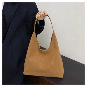 Detail of soft light brown hobo bag showing minimalist handle and matte leather texture