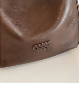Detailed macro shot of the premium brown leather texture and embossed logo plaque