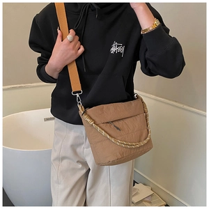 Detail showing brown nylon bucket bag with yellow fabric strap and woven rope handle