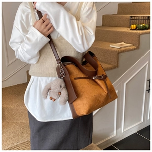 Close-up of retro bucket bag with pleated texture and plush rabbit pendant detail