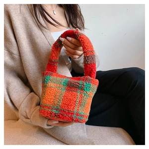 Detail of plush lamb wool bucket bag featuring orange and green plaid texture