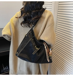 Detail of black leather hobo bag with contrast white stitching and gold hardware