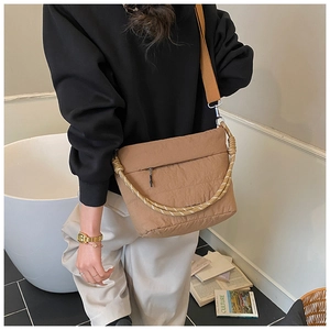 Detail of quilted khaki crossbody bag featuring a spiral braided handle and nylon texture