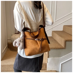 Detail of caramel bucket bag with pleat texture and plush rabbit charm on model